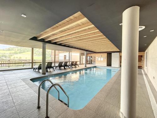 - une piscine dans un bâtiment avec des chaises et des tables dans l'établissement Demi-chalet de luxe avec piscine et vue Mont Blanc - FR-1-560-71, à Combloux