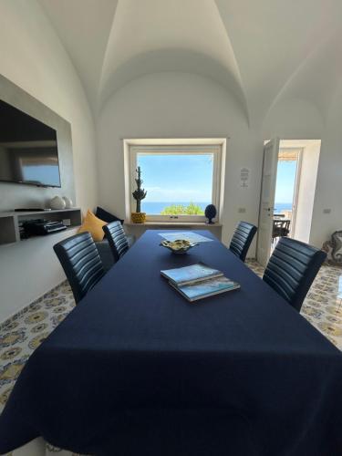 a dining room with a blue table and chairs at Villa La Panoramica Sea View in Capri