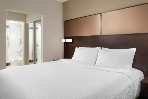a bedroom with a large white bed and a bathroom at Residence Inn by Marriott Ottawa Airport in Ottawa