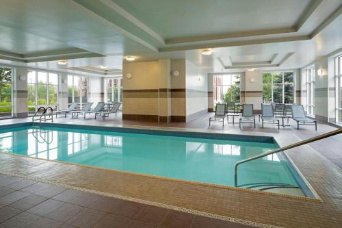 a swimming pool in a building with chairs and tables at Residence Inn by Marriott Ottawa Airport in Ottawa
