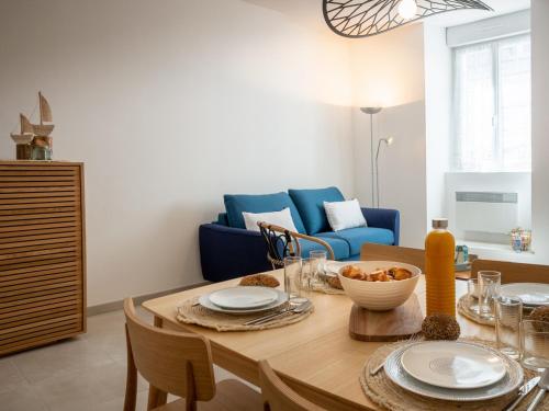 une salle à manger avec une table et un canapé bleu dans l'établissement Duplex charmant T3/4 à 150m des criques, court commune, proche bourg à Port-Louis - FR-1-349-170, à Port-Louis