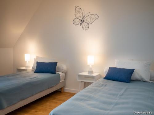 - une chambre avec 2 lits dotés d'oreillers bleus et d'un papillon sur le mur dans l'établissement Duplex charmant T3/4 à 150m des criques, court commune, proche bourg à Port-Louis - FR-1-349-170, à Port-Louis