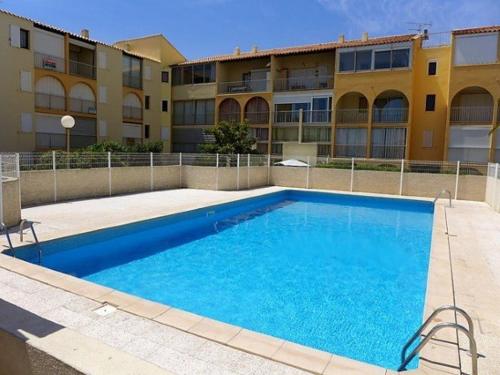 une grande piscine bleue devant un immeuble dans l'établissement Pavillon 2 pièces avec mezzanine, 6 couchages, terrasse, piscine, proche plage - Narbonne Plage - FR-1-229B-45, à Narbonne