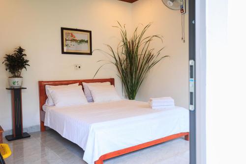 a bedroom with a bed with white sheets and a plant at Heartfelt Hideaway in Vũ Lâm