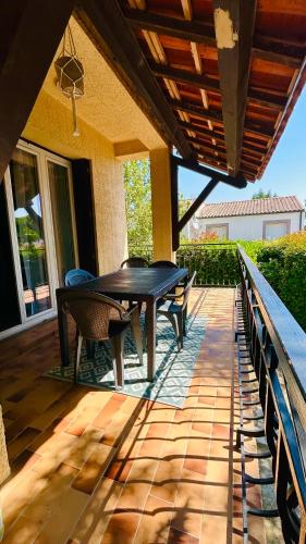 a patio with a table and chairs on a porch at Chez le Grand in Maraussan
