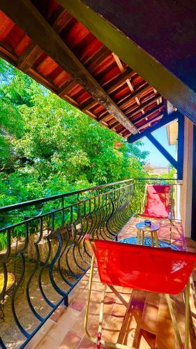 a red chair on a balcony with trees in the background at Chez le Grand in Maraussan