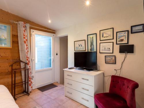 a bedroom with a dresser with a television and a red chair at Chambres d'Hôte Air Marin in Lannion
