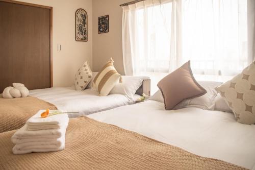 a bedroom with two beds with white sheets and pillows at Direct to Shinjuku Two bedrooms Higashi-Nakano Station Free luggage storage in Wada