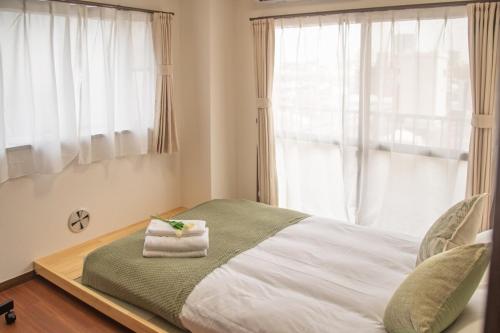 a bedroom with a bed with a towel on it at Direct to Shinjuku Two bedrooms Higashi-Nakano Station Free luggage storage in Wada