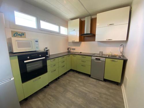 La cuisine est équipée de placards verts et d'un four micro-ondes. dans l'établissement Charmant T2 rénové avec balcon et parking, accès direct plage - Saint Brevin - FR-1-364-115, à Saint-Brévin-les-Pins
