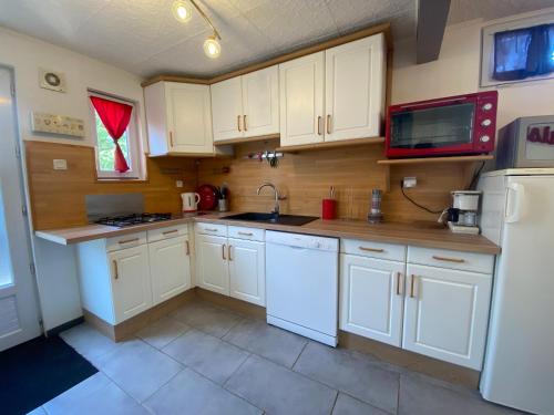 une cuisine avec des armoires blanches, un évier et un réfrigérateur dans l'établissement Maison familiale avec terrasse et proche plage à Saint-Brevin-les-Pins - FR-1-364-98, à Saint-Brévin-les-Pins