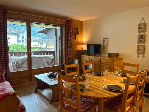 une salle à manger avec une table avec des chaises et une télévision dans l'établissement Appartement 52m², Terrasse, Parking, Cœur de Samoëns, Ski & Commerces Proches - FR-1-624-19, à Samoëns