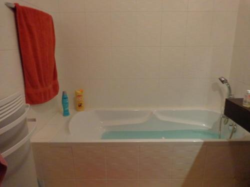 La salle de bains est pourvue d'une baignoire et d'une serviette rouge. dans l'établissement Duplex de Charme - Proche Plage, Port & Rues Piétonnes avec Parking Privé - FR-1-331-6, à Les Sables-dʼOlonne