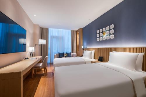 a hotel room with two beds and a desk at Orange crystal Beijing Changying Fudi V Center Hotel in Beijing