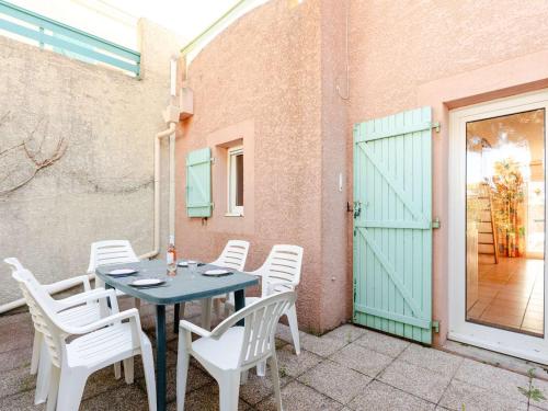 une table et des chaises sur une terrasse avec une porte verte dans l'établissement Pavillon 3 pièces proche plage du Grazel, climatisation, parking privé - FR-1-409-84, à Gruissan