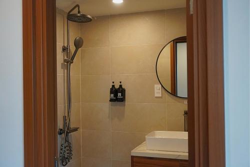 a bathroom with a shower with a sink and a mirror at QR Hotel Dalat in Xuan An