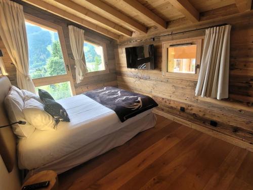 a bedroom with a bed in a log cabin at Chalet cozy à 4* avec cheminée, WiFi, et balcon proche des pistes aux Gets - FR-1-598-89 in Les Gets
