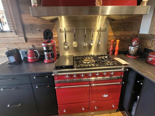 Il comprend une cuisine équipée d'une cuisinière rouge. four supérieur dans l'établissement Chalet cozy à 4* avec cheminée, WiFi, et balcon proche des pistes aux Gets - FR-1-598-89, aux Gets