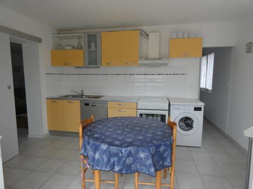 une cuisine avec une table et une machine à laver dans l'établissement Maison familiale à Notre-Dame-de-Monts - Plage à 600m, jardin, 3 chambres, confort moderne - FR-1-540-153, à Notre-Dame-de-Monts