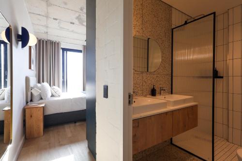 a bathroom with a tub and a sink and a bed at THREE43 ON B - Fluent Serviced Apartments in Cape Town