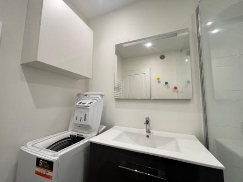 une salle de bain blanche avec un lavabo et un miroir dans l'établissement Appartement Moderne Centre-Ville, Proche Plage, 5 Couchages, Parking Privé - FR-1-197-555, à Les Sables-dʼOlonne