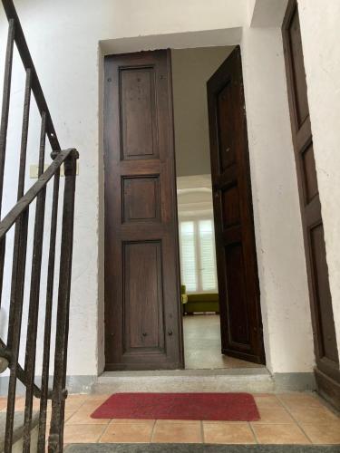 an empty hallway with a wooden door and stairs at Casa sulla Piazzetta in Saluzzo
