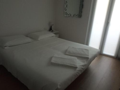 a white bed in a room with two towels on it at Casa sulla Piazzetta in Saluzzo