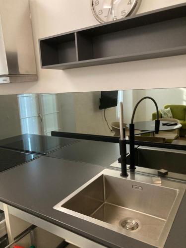 a kitchen counter with a sink and a clock at Casa sulla Piazzetta in Saluzzo