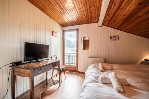 a bedroom with a bed and a desk with a television at Chalet Chez Juju in Abondance
