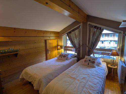deux lits dans une chambre avec une fenêtre dans l'établissement Ski au pied, duplex rénové 4 ch, terrasse, cheminée, tout confort - FR-1-459-22, à La Clusaz