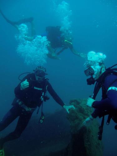 three people are scuba diving in the ocean at Florida Blue Bay Resort & Spa in Psathopirgos