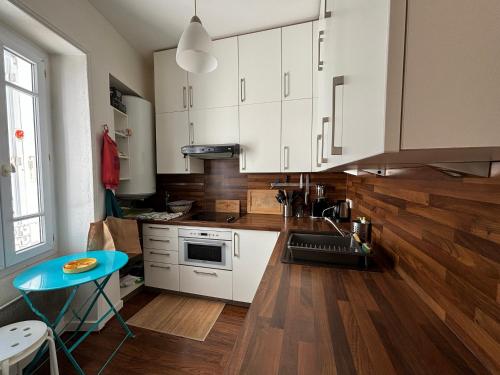 une cuisine avec des placards blancs et une table bleue dans l'établissement Appartement cosy au centre, à deux pas de la plage, tout équipé pour 4 personnes - FR-1-197-330, à Les Sables-dʼOlonne