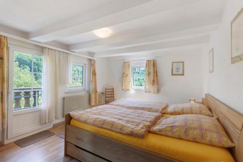 a bedroom with a large bed and two windows at Ferienwohnungen Demberg in Schmallenberg