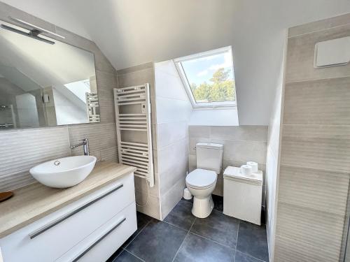 une salle de bain avec un lavabo et des toilettes et une fenêtre dans l'établissement Maison rénovée proche mer 7 pers., jardin, wifi et ping-pong, 3 chambres, 2 salles d'eau - FR-1-361-426, à Carolles