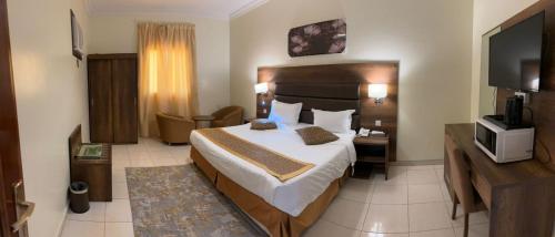 a hotel room with a bed and a television at Rahwan Palace Serviced Apartments in Baljurashi