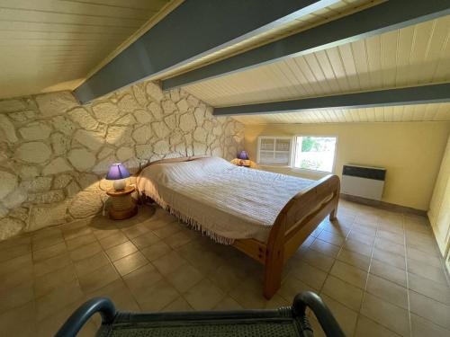 une chambre avec un lit et un mur en pierre dans l'établissement Charmant Pavillon Familial avec Terrasse et Mezzanine - Proche Plage - Saint-Cyprien Plage - FR-1-106-86, à Saint-Cyprien