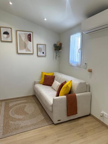 - un salon avec un canapé blanc et des oreillers jaunes dans l'établissement Charmant studio près de Roissy CDG, au Mesnil-Amelot