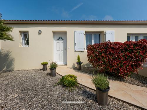 une maison avec une haie rouge devant elle dans l'établissement Maison 3 chambres aux Sables-d'Olonne avec jardin clos, véranda et proche commerces et plages. - FR-1-197-576, à Les Sables-dʼOlonne