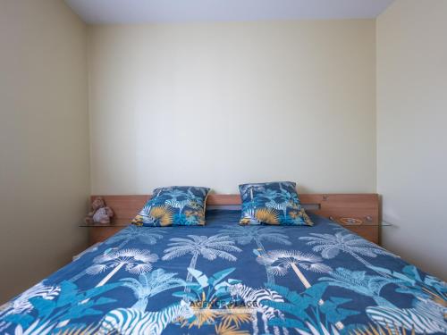 - une chambre avec un lit bleu et 2 oreillers dans l'établissement Maison 3 chambres aux Sables-d'Olonne avec jardin clos, véranda et proche commerces et plages. - FR-1-197-576, à Les Sables-dʼOlonne