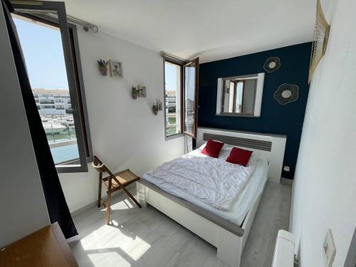 une chambre avec un lit avec deux oreillers rouges dans l'établissement T2 rénové avec cabine, piscine, animaux admis, parking à 500m de la plage - FR-1-106-49, à Saint-Cyprien