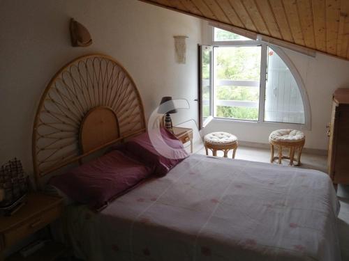 une chambre avec un grand lit et deux chaises dans l'établissement Charmante maison avec piscine & accès plage, 500m de la mer, La Tranche-sur-Mer, 4 pers. - FR-1-357-274, à La Tranche-sur-Mer