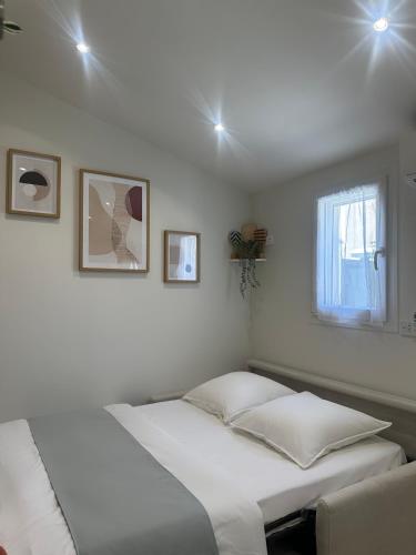 une chambre blanche avec un lit et une fenêtre dans l'établissement Charmant studio près de Roissy CDG, au Mesnil-Amelot