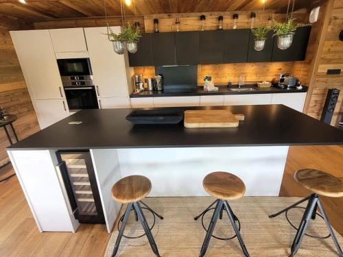 une cuisine avec un comptoir noir et trois tabourets dans l'établissement Chalet de luxe avec jacuzzi, sauna, parking et WIFI aux Gets - FR-1-598-19, aux Gets