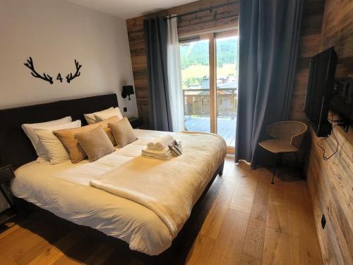une chambre avec un grand lit et une fenêtre dans l'établissement Chalet de luxe avec jacuzzi, sauna, parking et WIFI aux Gets - FR-1-598-19, aux Gets