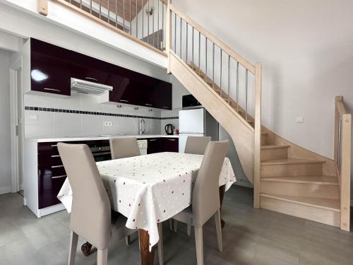 une salle à manger avec une table, des chaises et un escalier dans l'établissement Maison 5 Pers à La Palmyre - Terrasse Sud, Plage à 1000m, Commerces à 300m, Calme, WIFI, Parking - FR-1-705-21, à La Palmyre