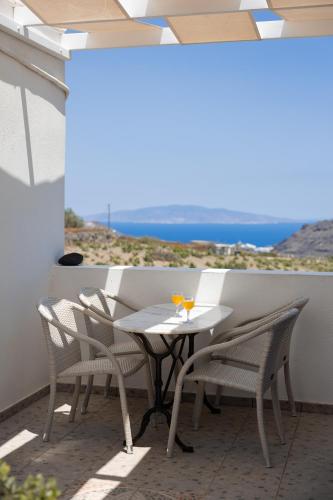 a table and chairs on a balcony with a view of the ocean at Villa Happening in Imerovigli