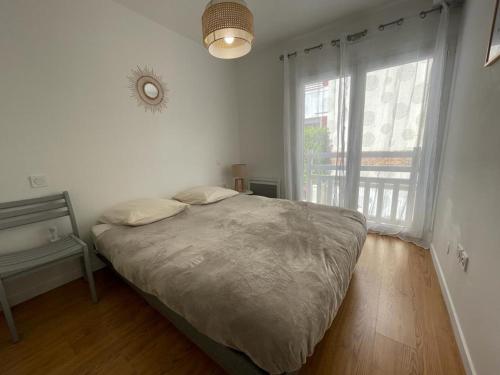 une chambre avec un lit et une grande fenêtre dans l'établissement Bel Appartement T2 en Centre-Ville d'Arcachon avec Balcon, à 200m de la Plage et Proche de la Gare - FR-1-474-243, à Arcachon