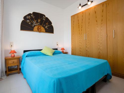 Schlafzimmer mit einem blauen Bett und einem Holzschrank in der Unterkunft Apartamento acogedor con piscina, WiFi y garaje cerca de la playa de La Farella, Llançà - ES-228-8 in Llança