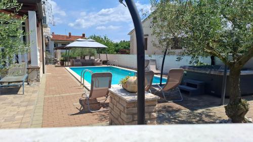 a swimming pool with chairs and a table and an umbrella at Apartments Kimm's Hideaway in Poreč