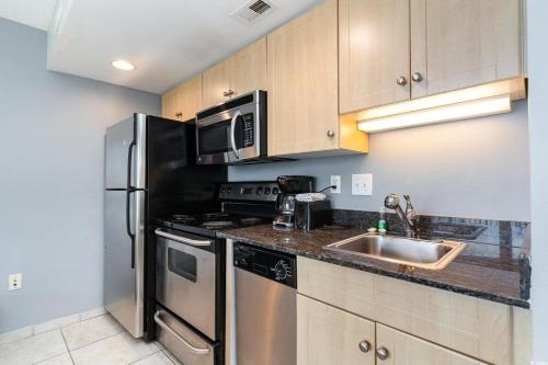 a kitchen with a stainless steel refrigerator and a sink at Oceanfront Luxury King Suite at Oceans One Resort in Myrtle Beach